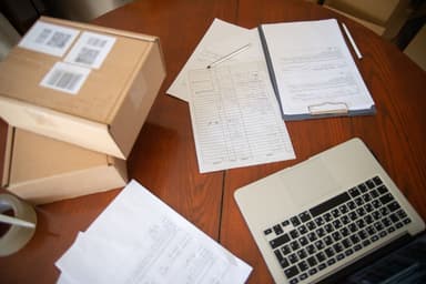 Laptop, pakketdozen en paperassen op een houten tafel