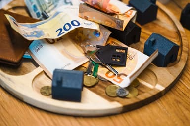 Miniatuurhuisjes, sleutels en eurogeld op een dienblad
