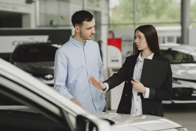 Verkoper en klant in gesprek bij een auto in de showroom