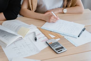 Student maakt aantekeningen met boeken en een rekenmachine