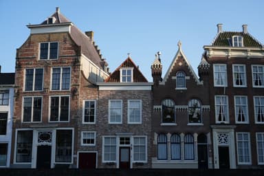 Rij historische Nederlandse grachtenpanden onder een blauwe lucht