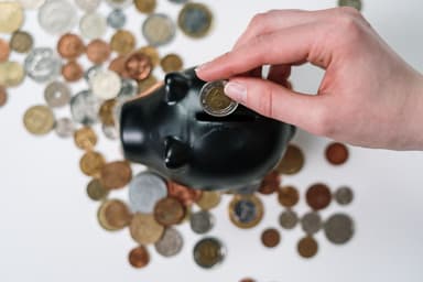 Hand stopt een munt in een zwart spaarvarken