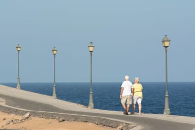 Ouder stel wandelt over een boulevard aan zee