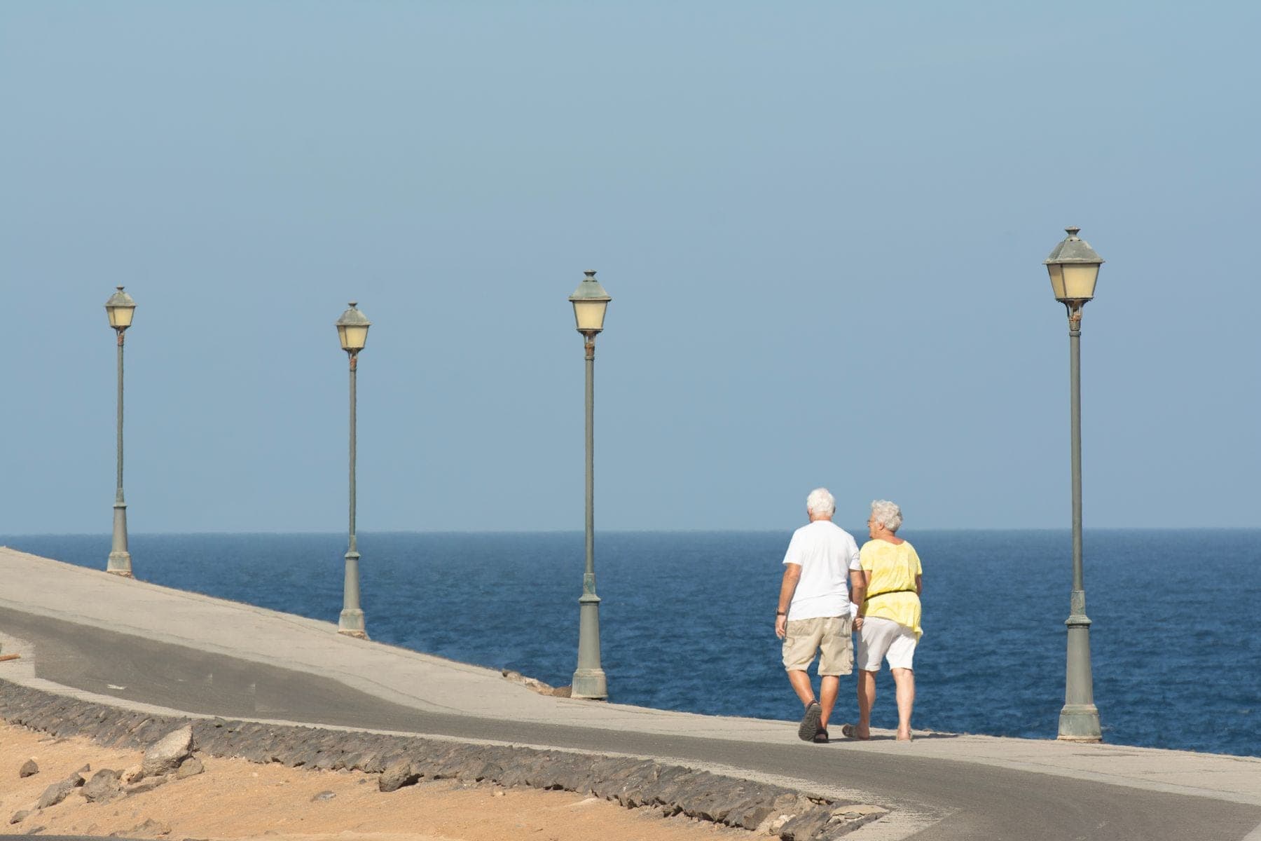 Ouder stel wandelt over een boulevard aan zee