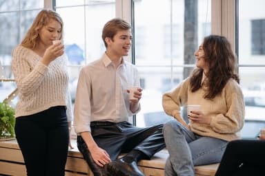 Drie vrienden praten met een kop koffie bij het raam