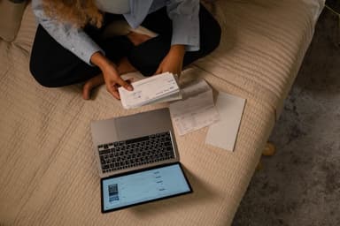Bovenaanzicht van iemand die met laptop en papieren de financiën ordent