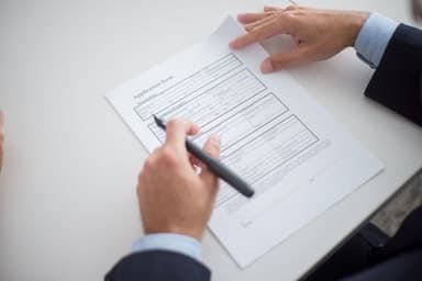 Hand met pen vult een aanvraagformulier in