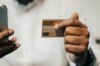 Hand met betaalkaart en smartphone bij een online betaling