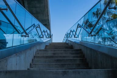 Betonnen trap met glazen leuningen naar een blauwe lucht