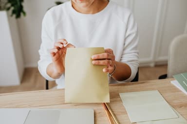 Vrouw sluit een bruine envelop aan een houten bureau