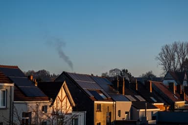 Rij woningen met zonnepanelen op de daken bij zonsondergang