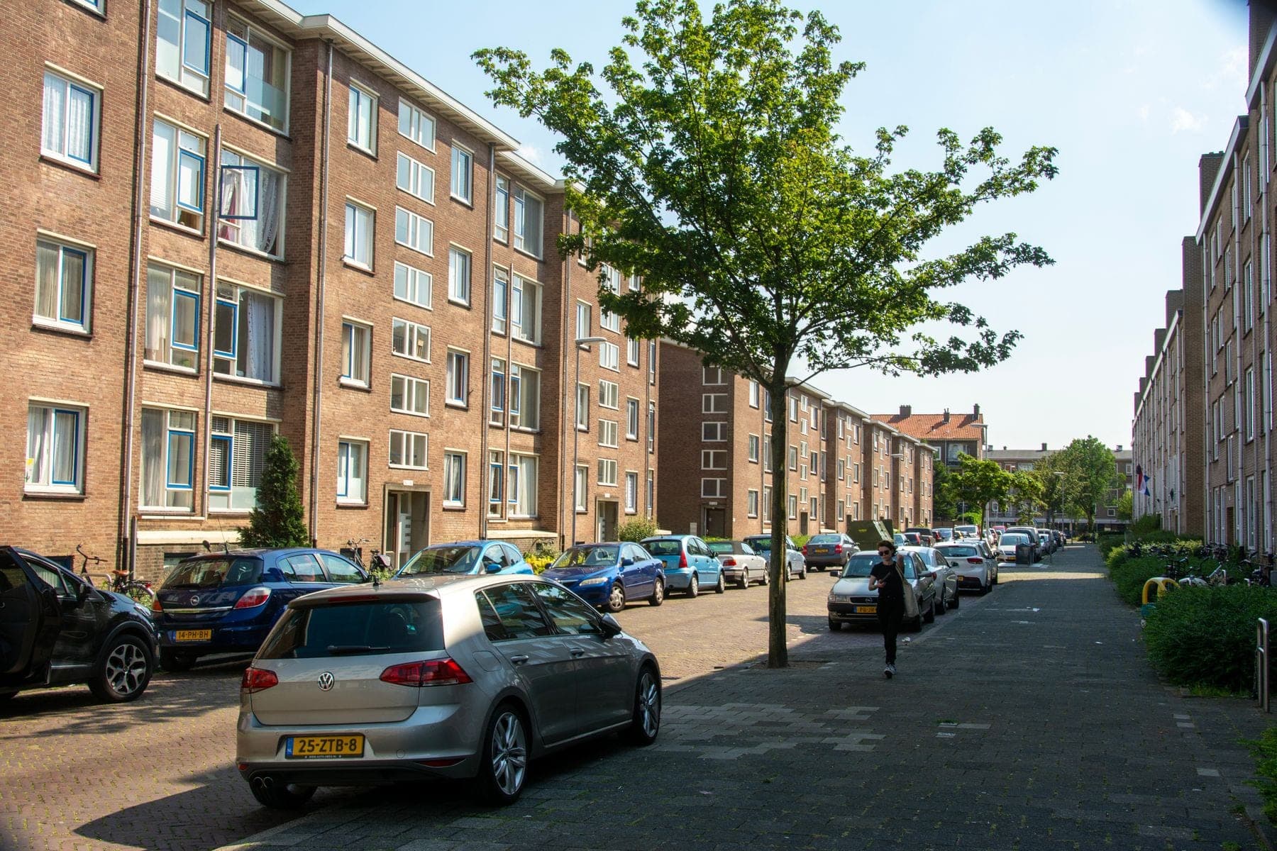Straat met geparkeerde auto's voor woonhuizen op een zonnige dag