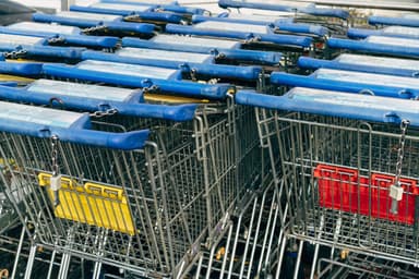 Rij in elkaar geschoven winkelwagens met blauwe handgrepen