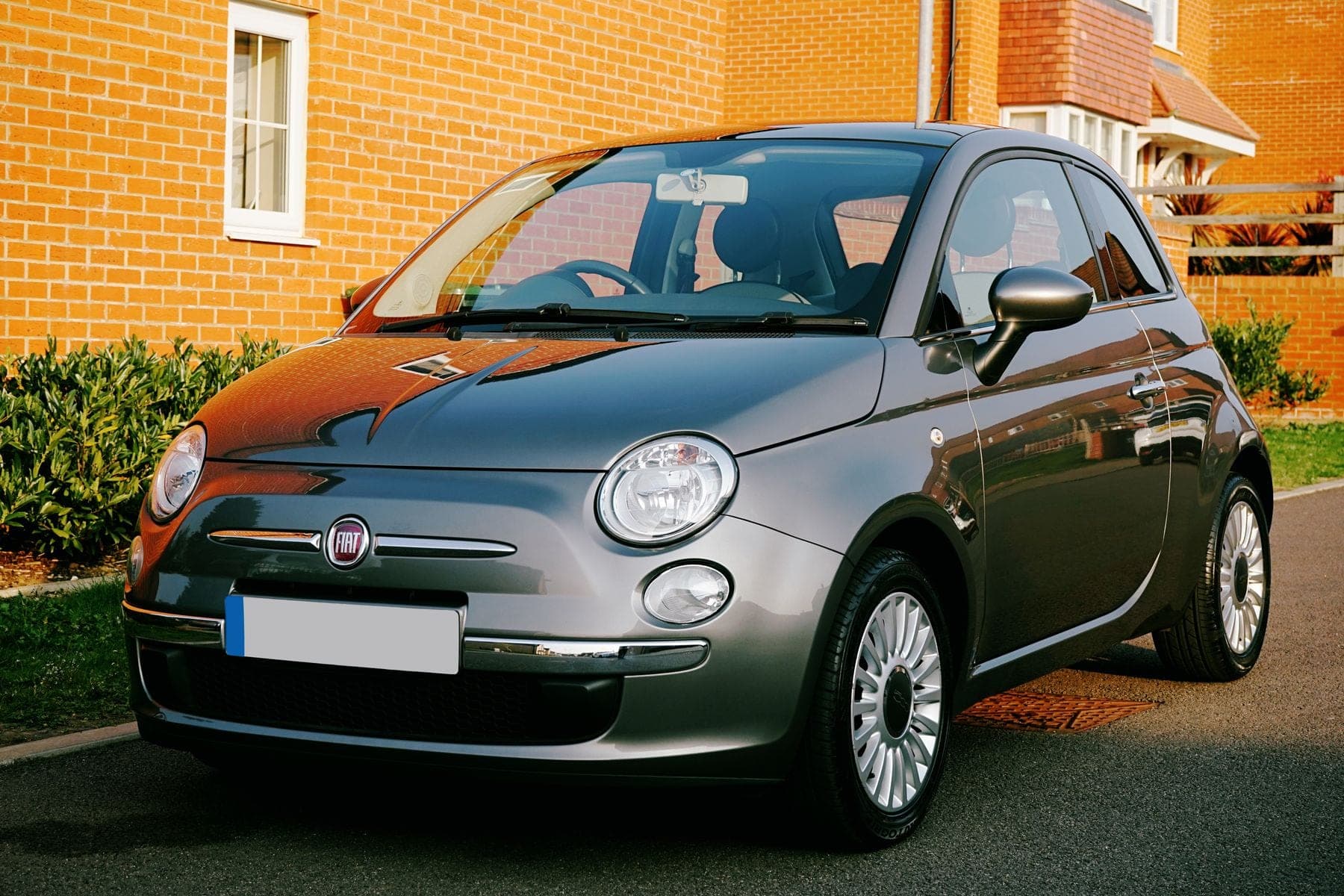 Zilvergrijze auto geparkeerd naast een huis van rode baksteen