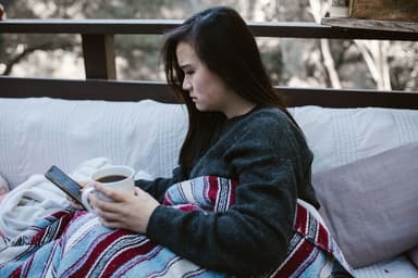 Vrouw met een kop koffie kijkt bedenkelijk naar haar telefoon
