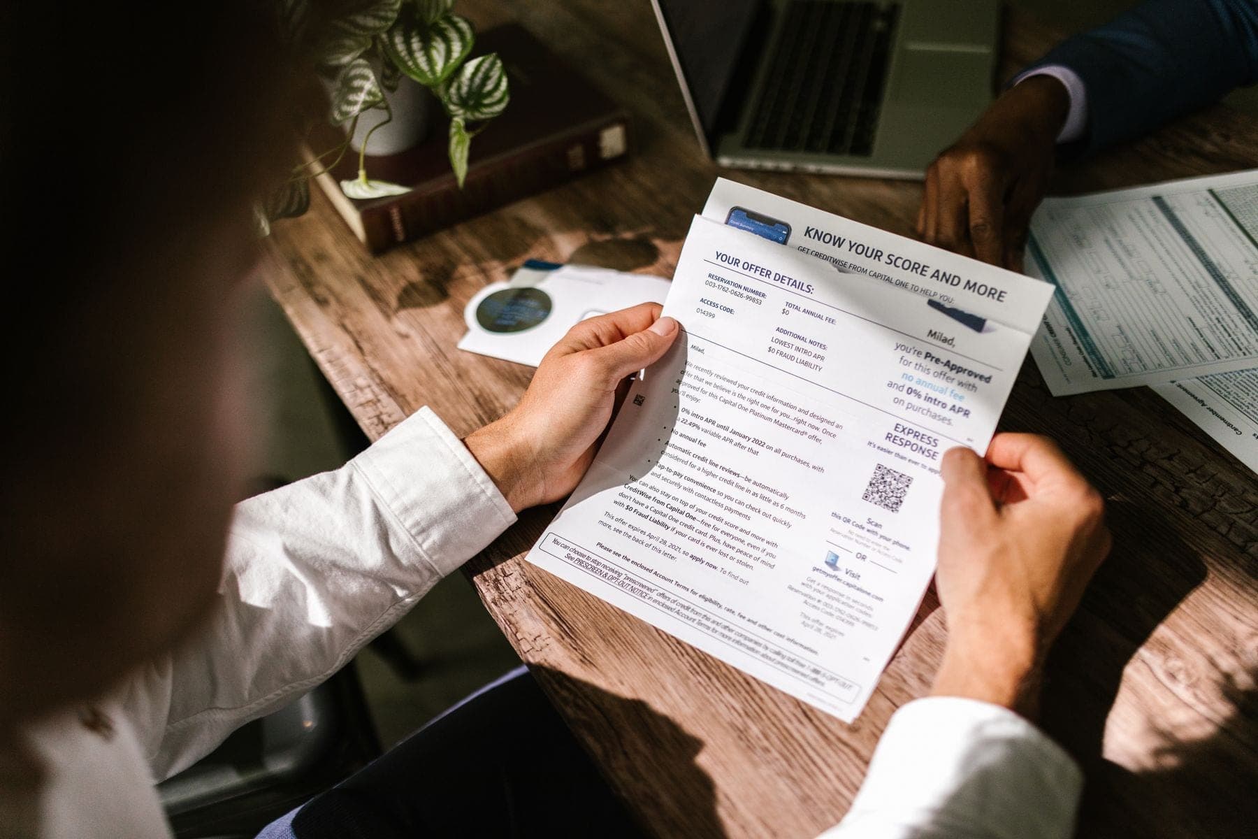 Man leest een financieel document aan een houten bureau bij daglicht