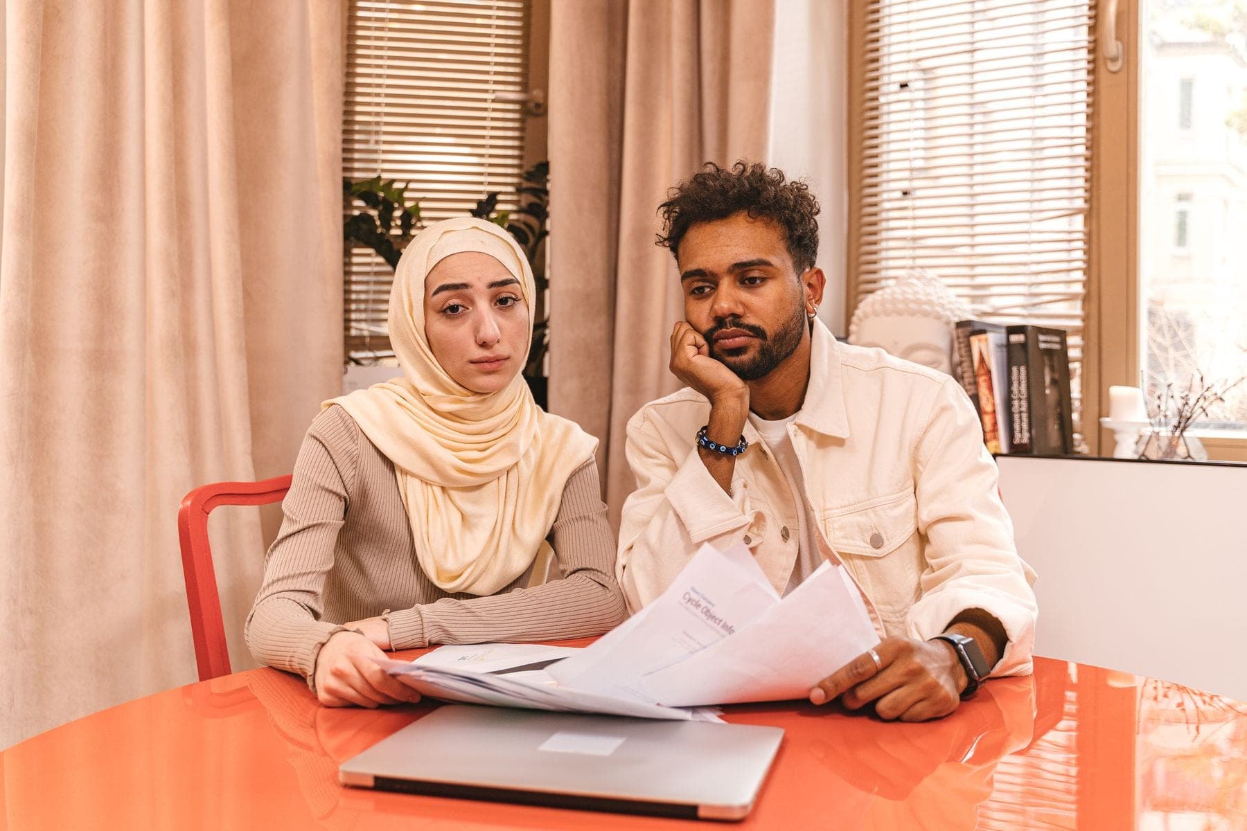 Man en vrouw bekijken samen papieren en een laptop aan tafel