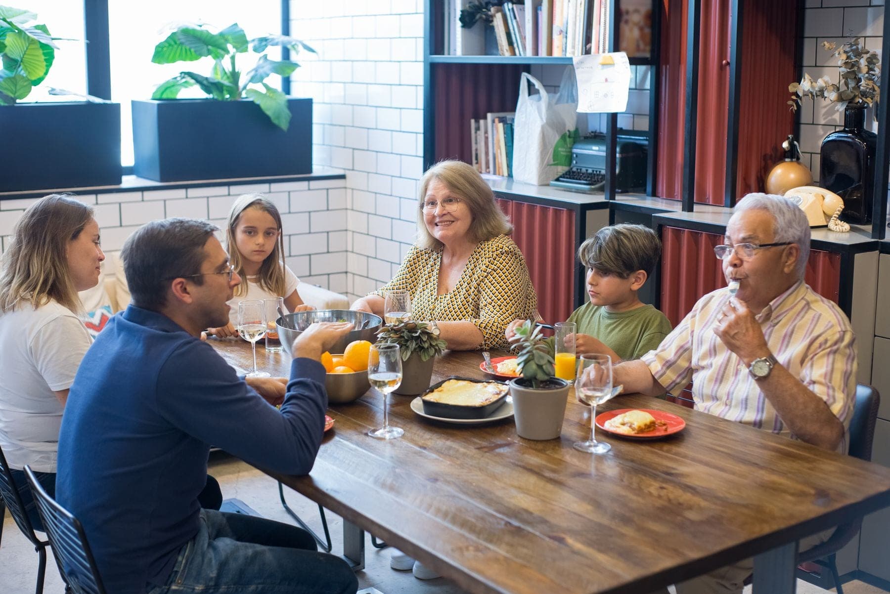 Grootouders, ouders en kinderen aan een houten eettafel tijdens een maaltijd