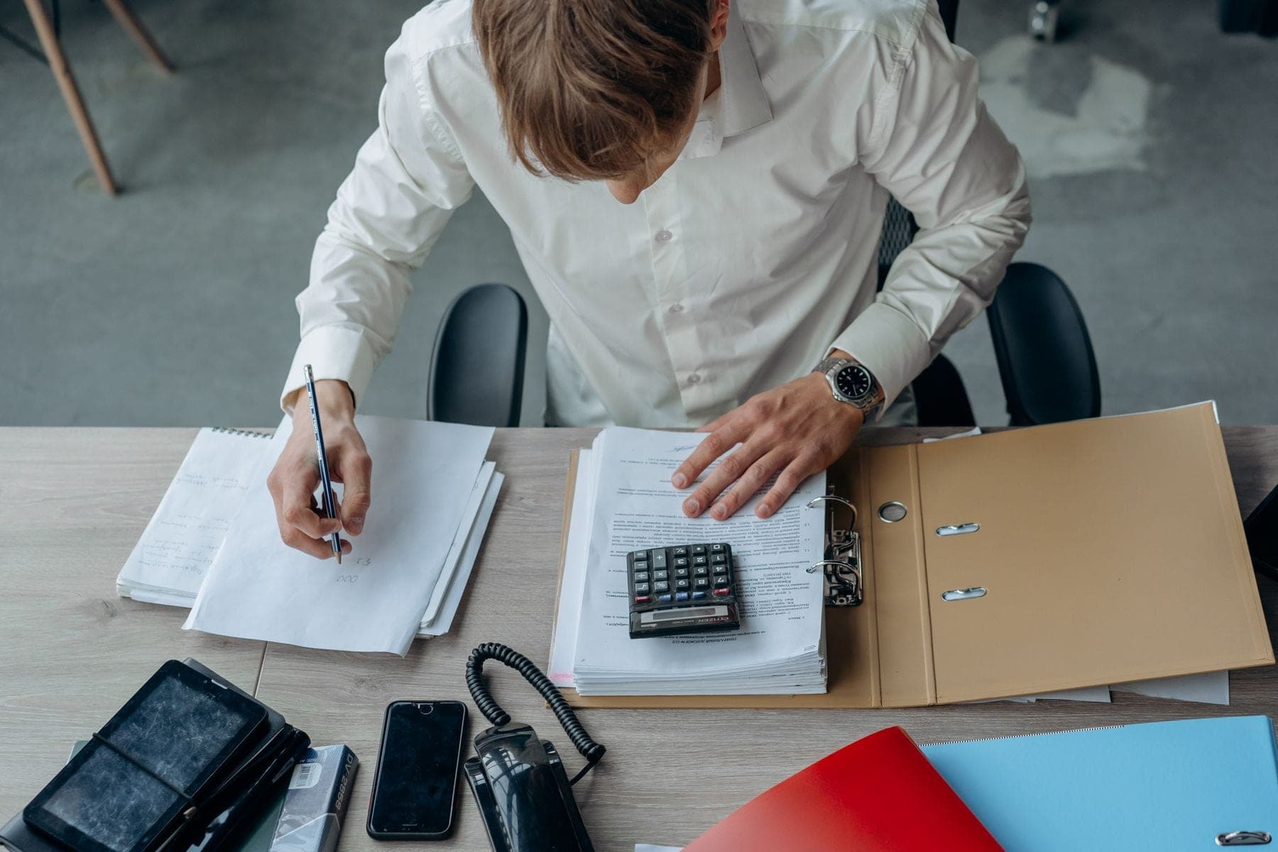 Man bekijkt financiële papieren met een rekenmachine aan een bureau