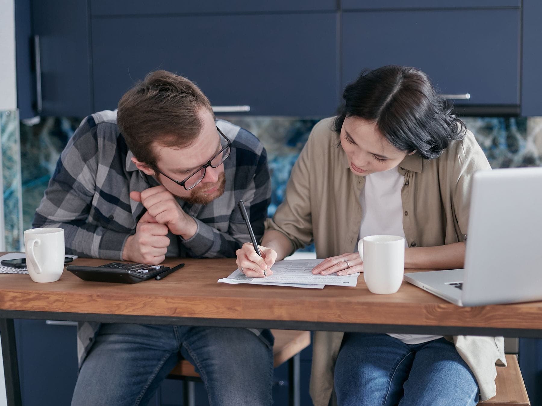 Stel aan de keukentafel rekent met een laptop, rekenmachine en papieren