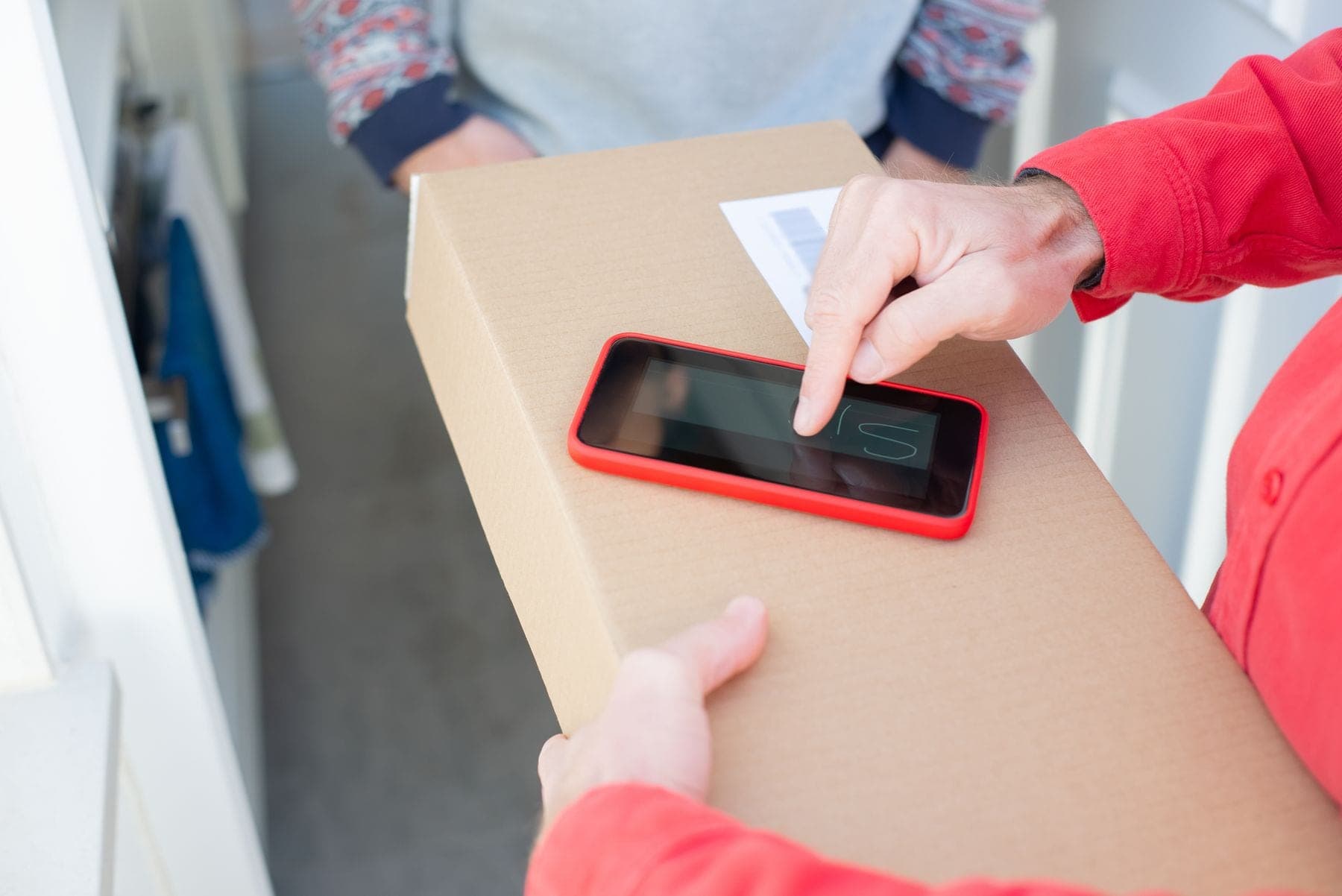 Pakketbezorger houdt een doos vast terwijl de klant op een telefoon tekent