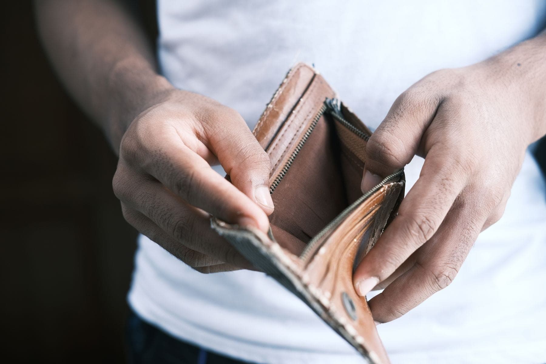 Twee handen houden een lege, opengeritste portemonnee open